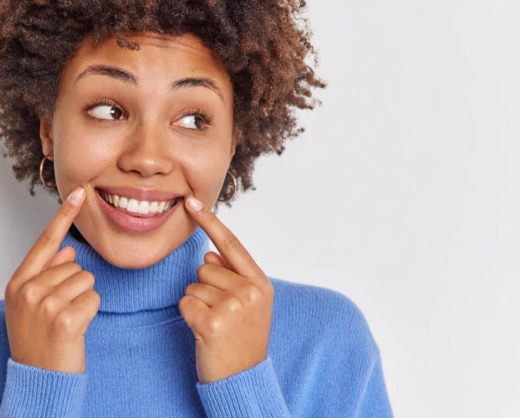 Chica sonriendo con los dedos en las comisuras